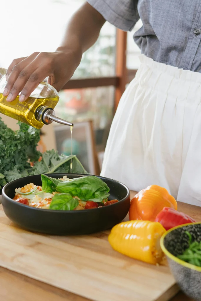 a photo of a woman pouring olive oil on vegetable.