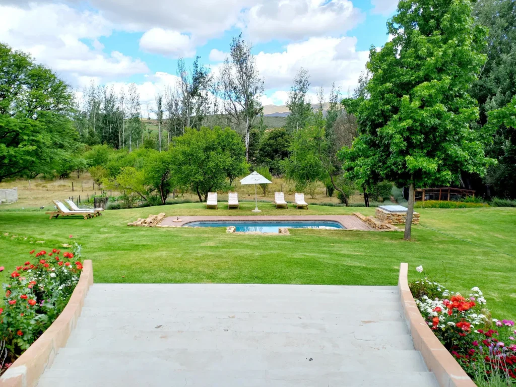 A scenic view of trees and a spa at Aloe Valley Retreat at Valley of a 100 Hills, with a background of scattered clouds in the sky.