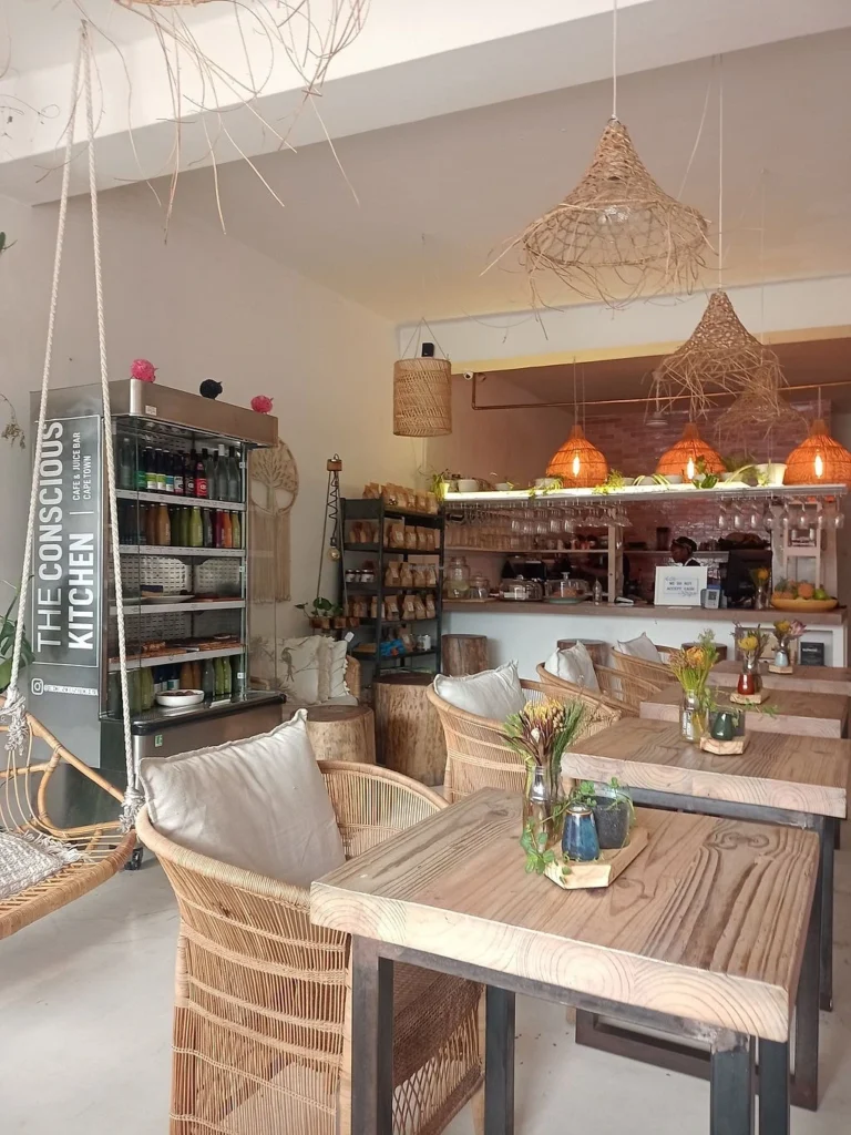 The interior of the Conscious Kitchen with brown tables and chairs and a display of glassware.